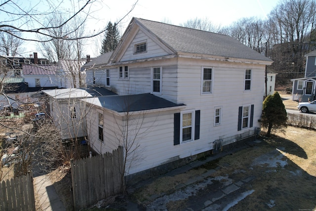 back of house featuring fence and roof with shingles