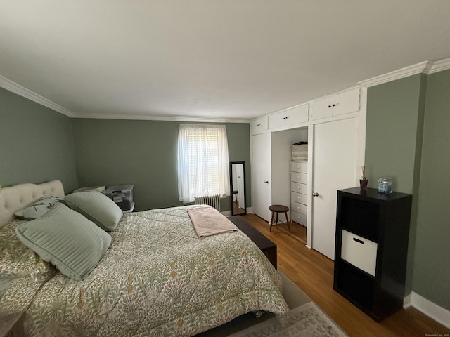 bedroom featuring baseboards, radiator, wood finished floors, and crown molding