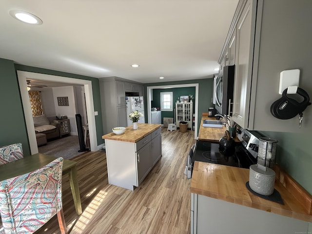 kitchen with gray cabinetry, butcher block countertops, appliances with stainless steel finishes, light wood-style floors, and a sink