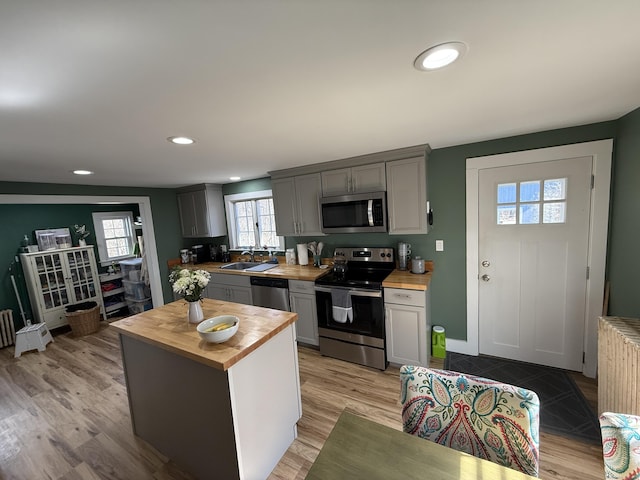 kitchen with a sink, stainless steel appliances, butcher block countertops, and gray cabinets