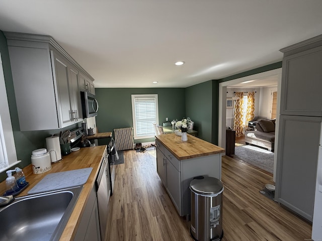 kitchen featuring radiator, wooden counters, gray cabinets, a sink, and appliances with stainless steel finishes