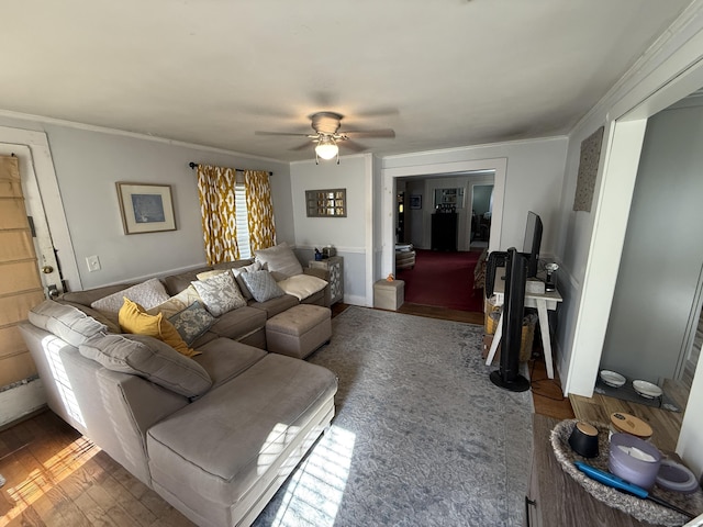 living area featuring ornamental molding, baseboards, a ceiling fan, and wood finished floors