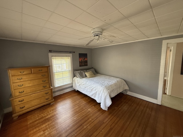 bedroom with baseboards, a ceiling fan, dark wood finished floors, and crown molding