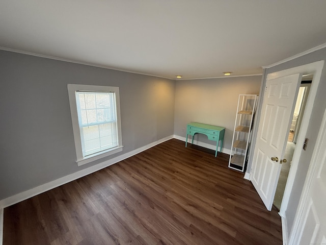 spare room with crown molding, dark wood-style floors, and baseboards