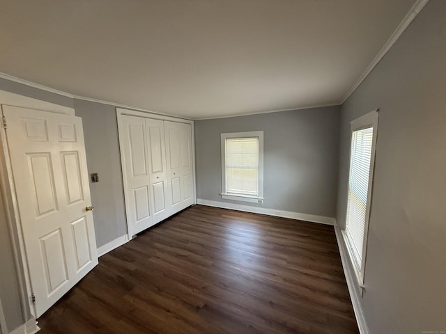 unfurnished bedroom featuring multiple windows, baseboards, dark wood finished floors, and ornamental molding