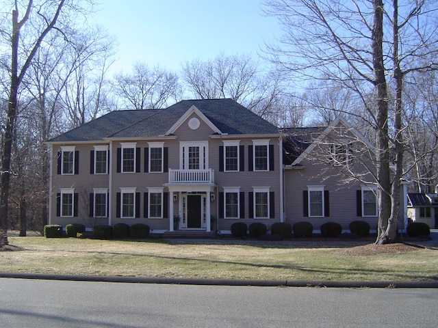 view of front of home with a balcony and a front lawn