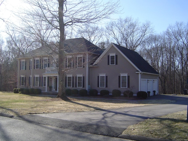 colonial-style house featuring aphalt driveway and a balcony