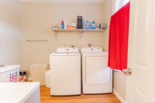 clothes washing area featuring washer and dryer, baseboards, light wood-style floors, and laundry area