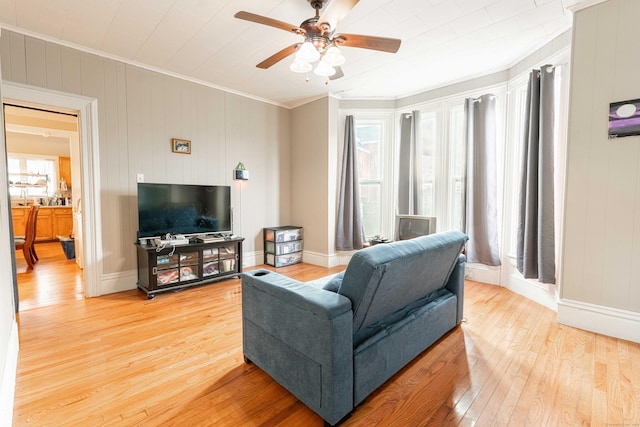 living area with a ceiling fan, light wood-style floors, and ornamental molding