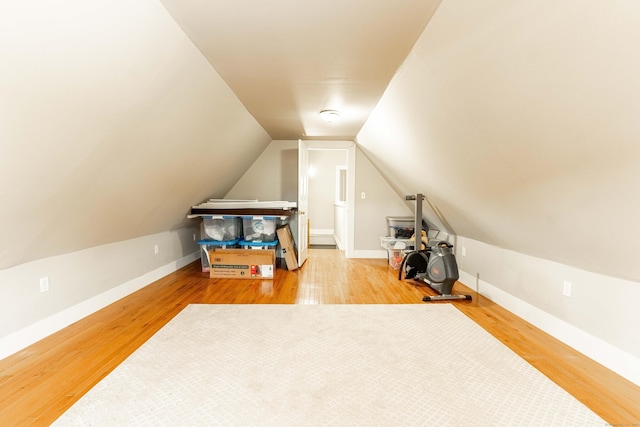 additional living space featuring baseboards, lofted ceiling, and wood finished floors