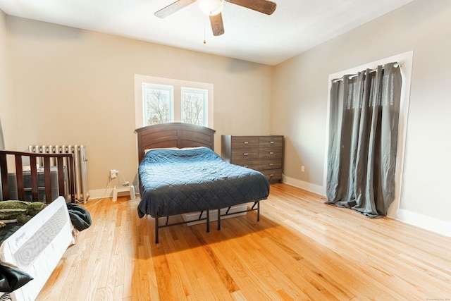 bedroom with baseboards, light wood-style floors, ceiling fan, and radiator heating unit