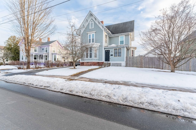 victorian-style house featuring a residential view, a chimney, and fence