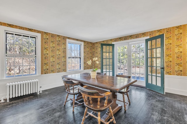 dining area with wood-type flooring, radiator, wainscoting, and wallpapered walls