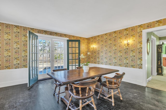 dining space with wallpapered walls, wood finished floors, french doors, and wainscoting