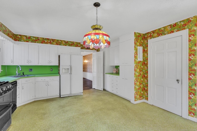 kitchen featuring a sink, white refrigerator with ice dispenser, white cabinets, and wallpapered walls