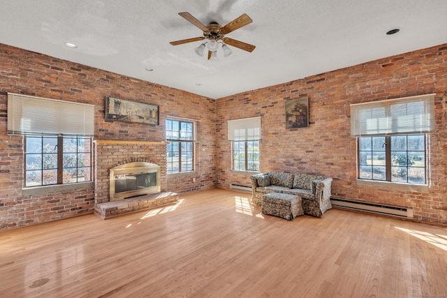 unfurnished living room featuring wood finished floors, baseboard heating, brick wall, and a fireplace