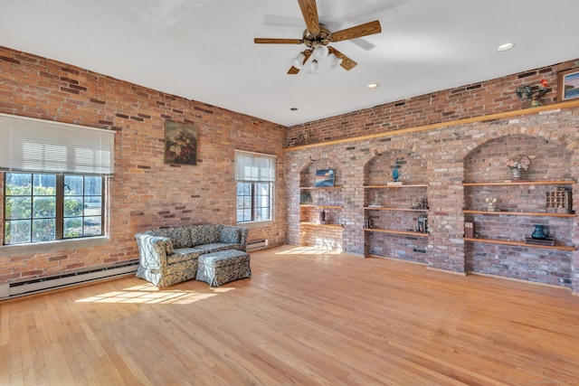 unfurnished room featuring wood finished floors, baseboard heating, brick wall, and a ceiling fan