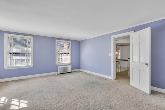 carpeted spare room featuring baseboards, radiator, and ornamental molding