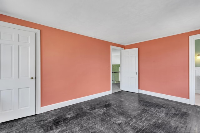 unfurnished room featuring baseboards and dark wood-type flooring