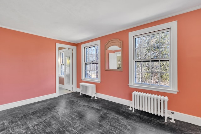 empty room featuring crown molding, radiator, wood finished floors, and baseboards