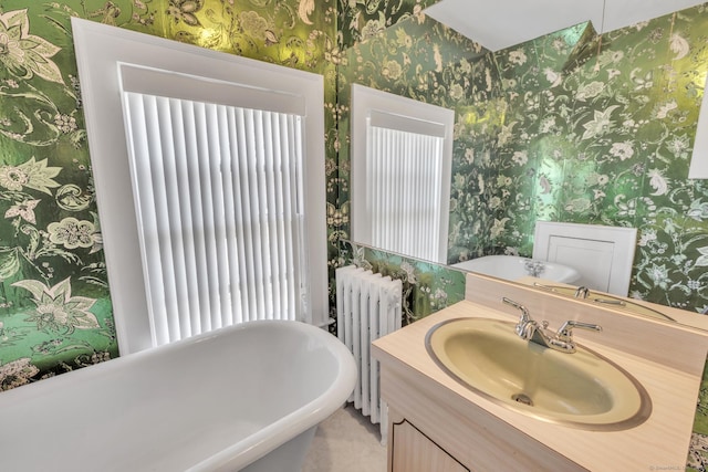 bathroom with a soaking tub, radiator, wallpapered walls, and vanity