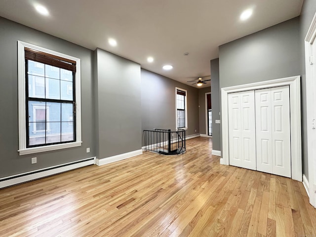 empty room with a ceiling fan, baseboards, a baseboard radiator, light wood-style flooring, and recessed lighting