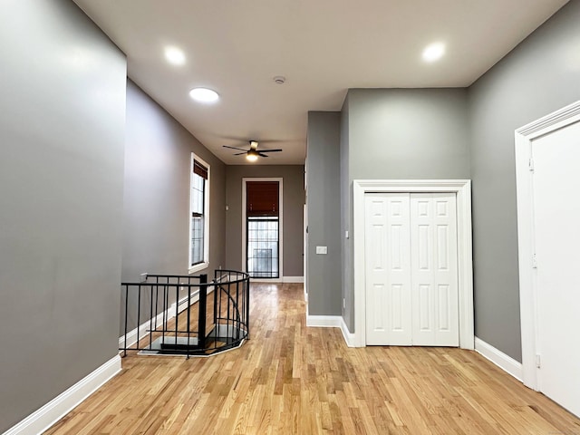 hallway featuring an upstairs landing, baseboards, and light wood-style floors