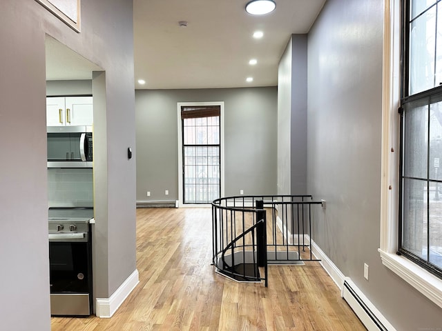 hall featuring light wood-type flooring, an upstairs landing, recessed lighting, baseboards, and baseboard heating