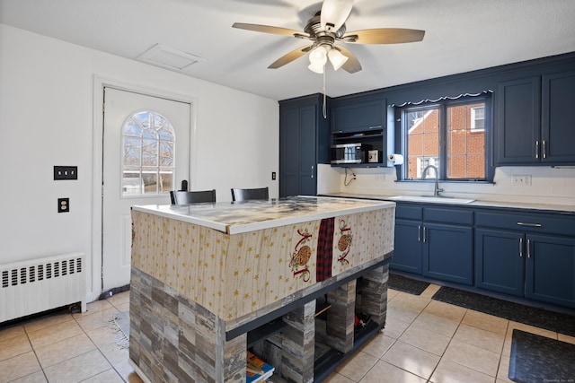 kitchen with blue cabinets, open shelves, radiator heating unit, and a sink