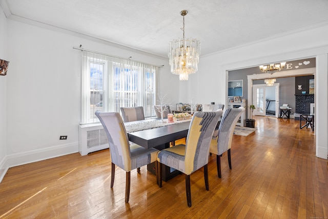 dining room with baseboards, a notable chandelier, hardwood / wood-style floors, and crown molding