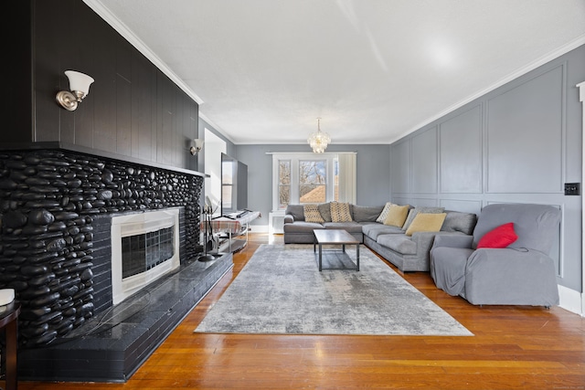 living room with a decorative wall, a fireplace, wood finished floors, and ornamental molding