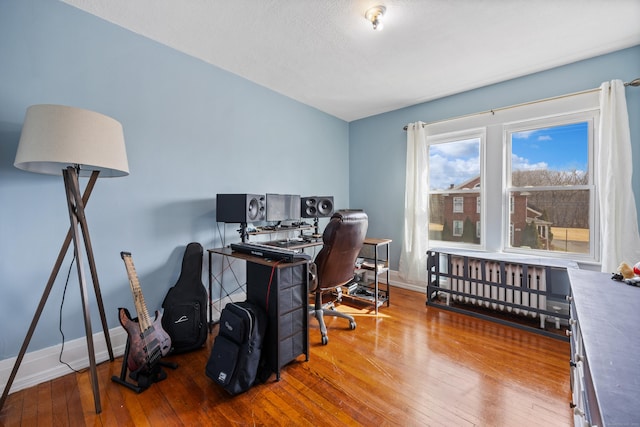 office space featuring hardwood / wood-style flooring, radiator heating unit, and baseboards