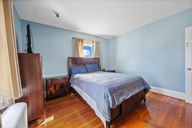 bedroom with radiator, baseboards, and wood-type flooring