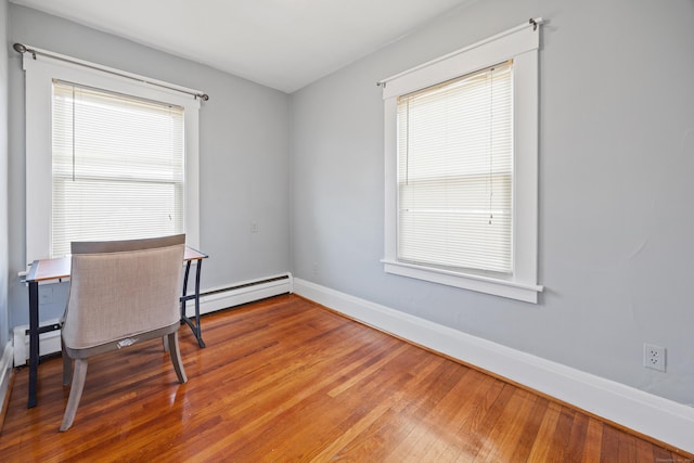 home office featuring baseboard heating, baseboards, and hardwood / wood-style floors