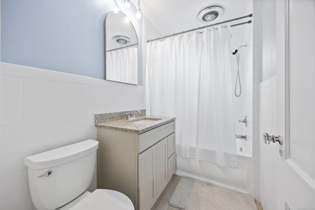 bathroom with tile walls, vanity, toilet, and shower / tub combo