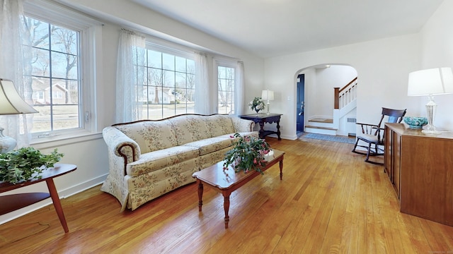 living room featuring a wealth of natural light, light wood-type flooring, and arched walkways