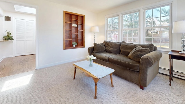 living room with a skylight, a baseboard heating unit, baseboards, and wood finished floors