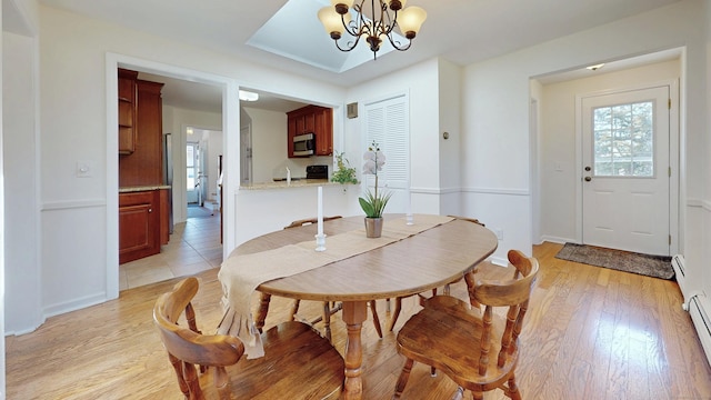 dining area with light wood-type flooring, baseboards, a notable chandelier, and baseboard heating