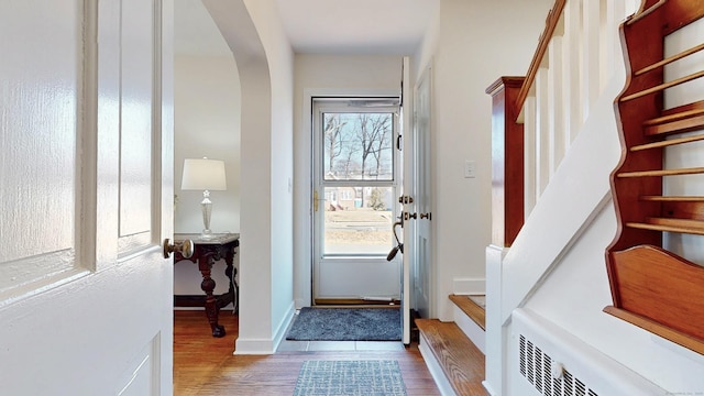 interior space with stairway, wood finished floors, arched walkways, and baseboards