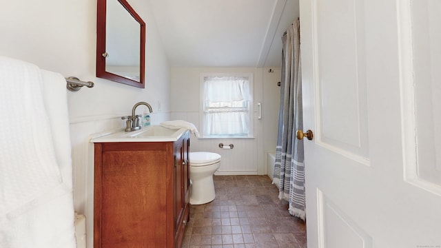 full bathroom featuring vanity, toilet, and a wainscoted wall