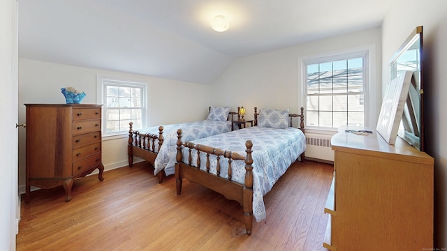 bedroom with radiator, vaulted ceiling, and light wood finished floors