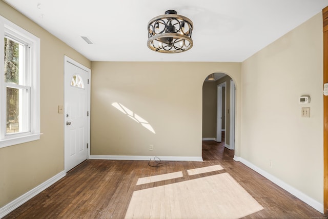 entryway with arched walkways, a healthy amount of sunlight, and wood finished floors