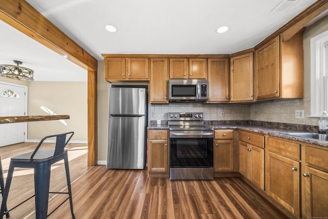 kitchen featuring dark countertops, stainless steel appliances, and brown cabinetry