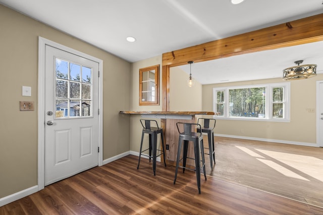 dining room with beamed ceiling, baseboards, and wood finished floors