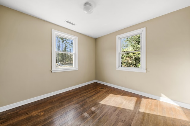 unfurnished room featuring visible vents, baseboards, and dark wood-style flooring