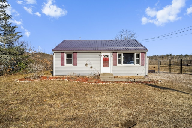 bungalow with entry steps, metal roof, a front lawn, and fence