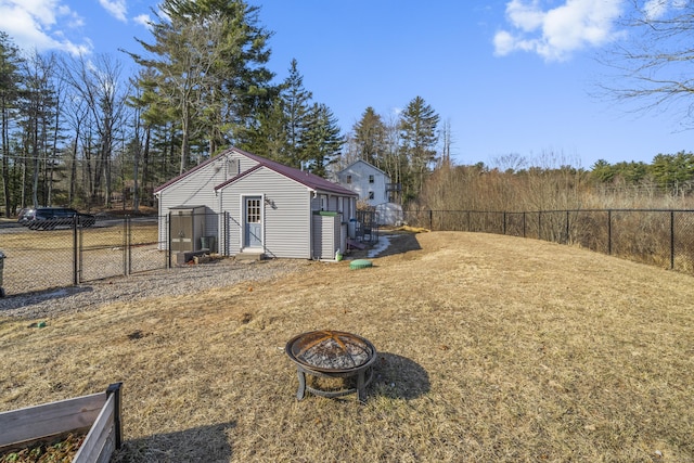 view of yard with an outdoor structure, a fenced backyard, and an outdoor fire pit