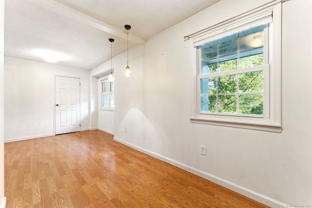 spare room featuring a textured ceiling, baseboards, and wood finished floors