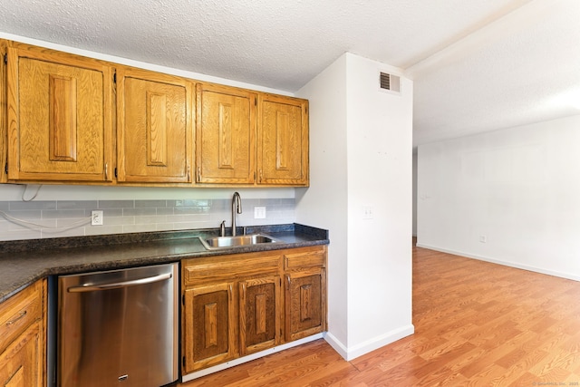 kitchen featuring dark countertops, brown cabinets, dishwasher, and a sink