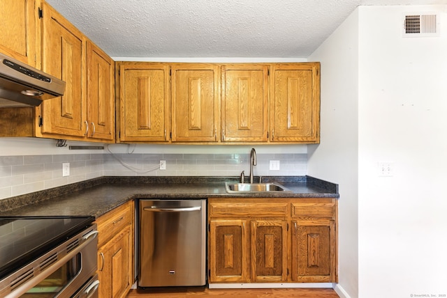 kitchen featuring a sink, visible vents, stainless steel dishwasher, and dark countertops